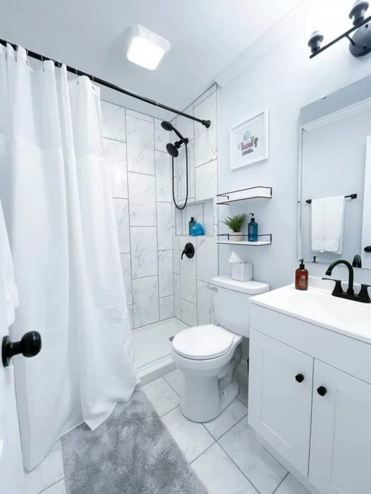 A modern, sparkling-clean bathroom featuring a walk-in shower, vanity with mirror, and toilet. The neutral palette and tidy presentation evoke a boutique-hotel feel, emphasizing comfort and freshness.