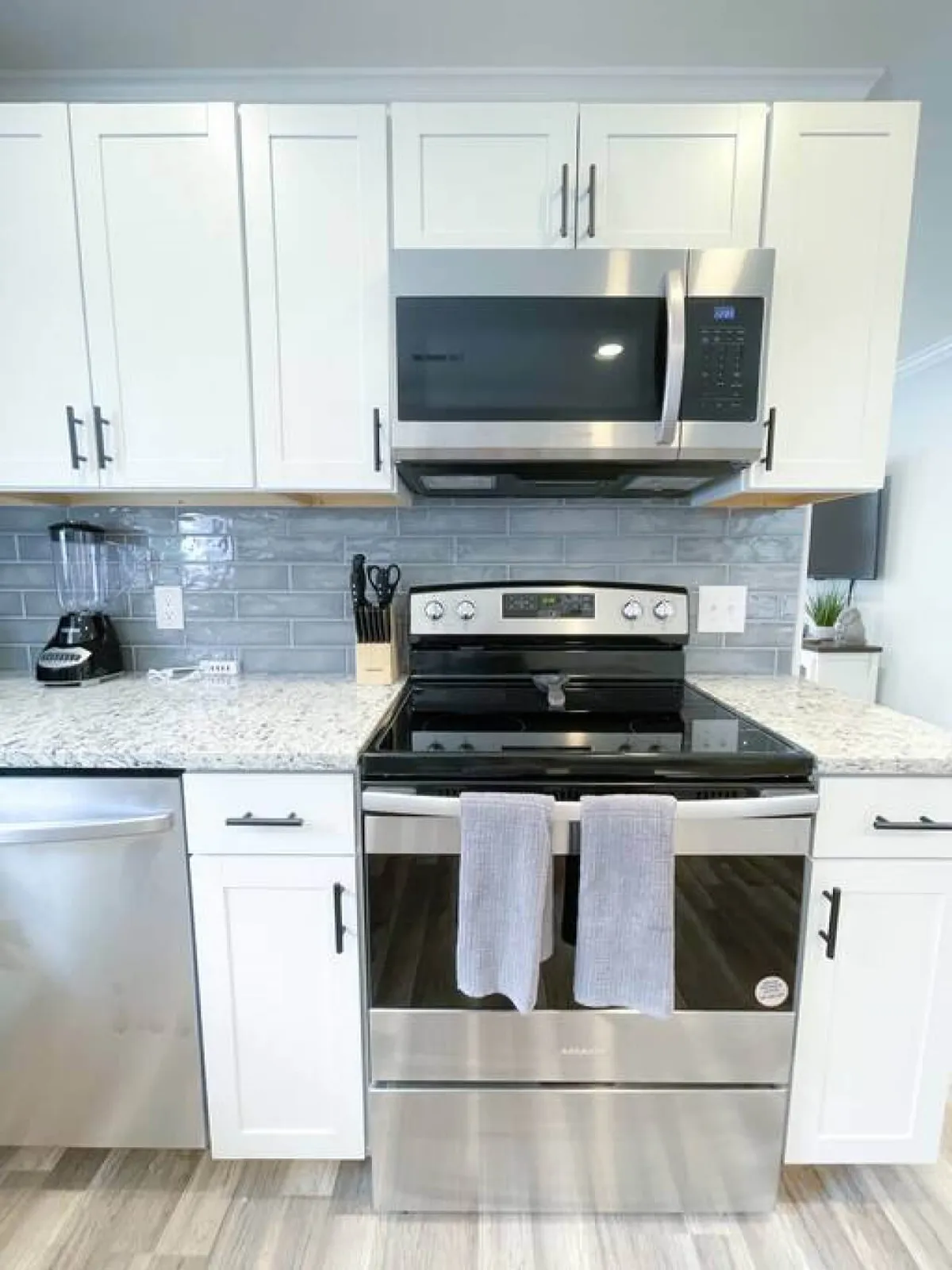 A cozy, modern kitchen vignette with stainless steel appliances, a granite countertop, and white cabinetry. The compact yet inviting space suggests comfort and convenience for families or business travelers enjoying home-cooked meals. The setup is practical for both everyday and special occasions.