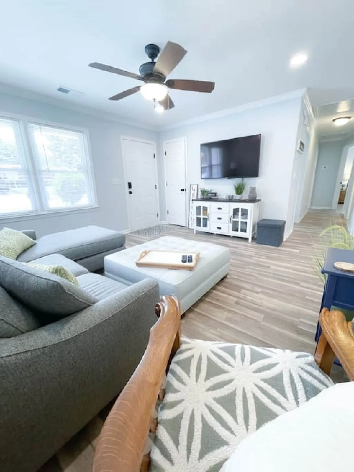 The photo features a large sectional sofa, a coffee table, a television, and a decorative console table, all arranged in a warm, inviting living room. Ample seating and a cozy atmosphere invite guests to relax and enjoy entertainment.
