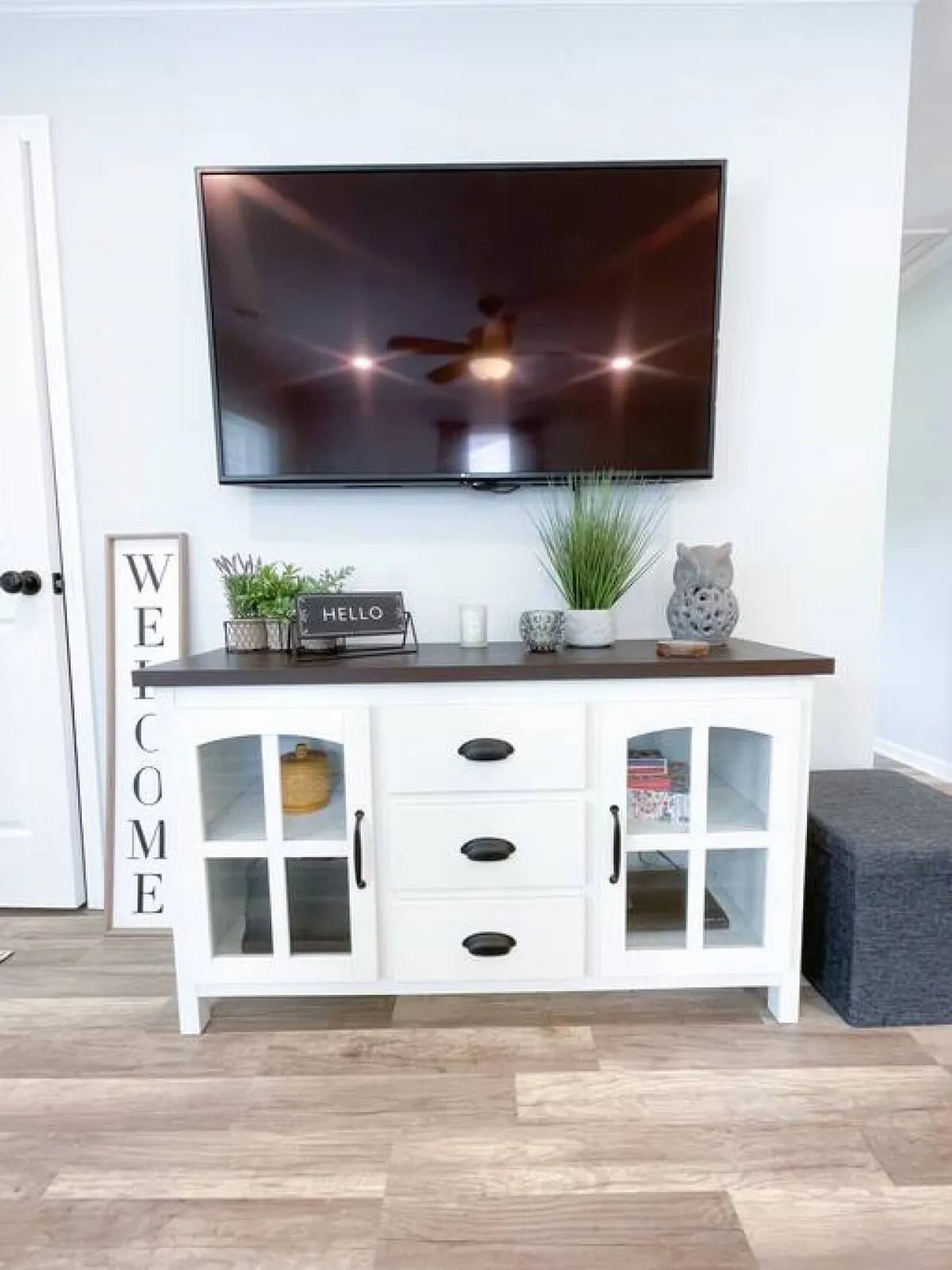 A comfortable living room featuring a television atop a console table, surrounded by decorative items. The arrangement invites relaxation or casual socializing, with an overall welcoming and modern aesthetic.